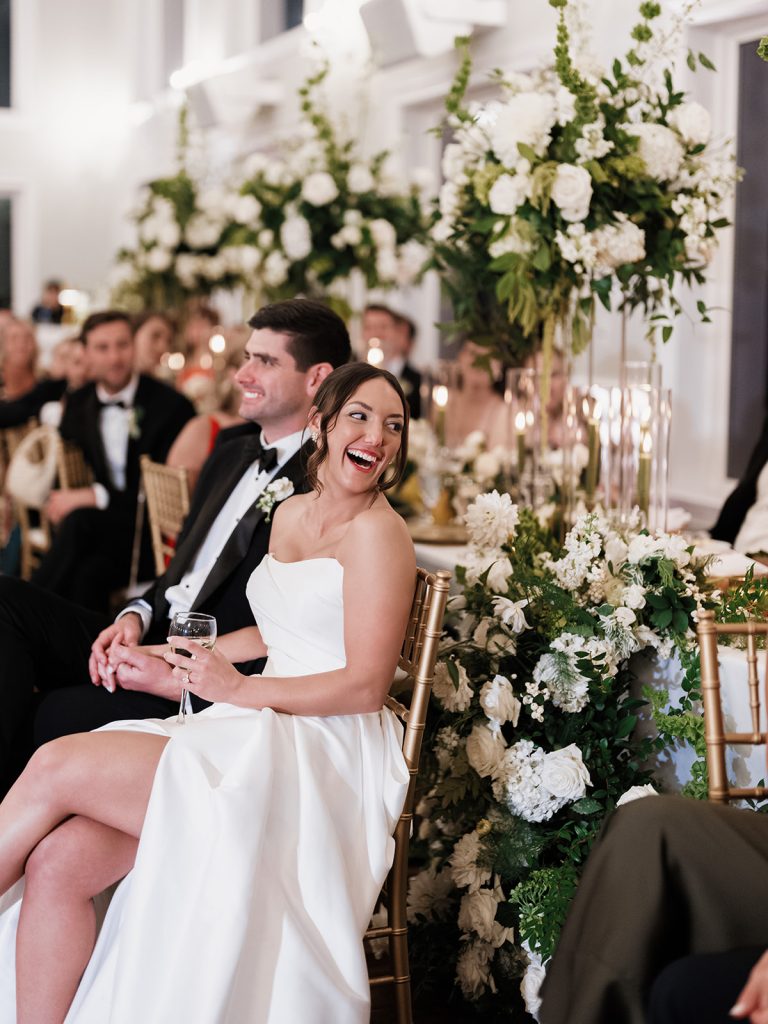 Bride and Groom laughing during wedding reception showing off all the floral details of their wedding day