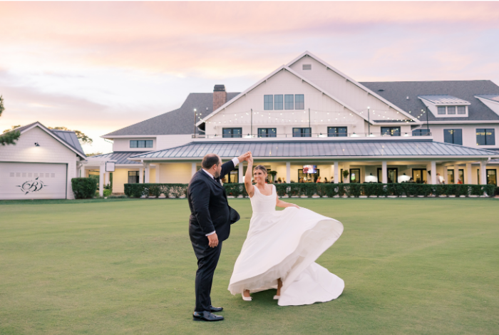 Bride and groom dancing on the lawn at Bayside Resort Golf Club in Selbyville, Delaware, with the clubhouse and sunset sky in the background