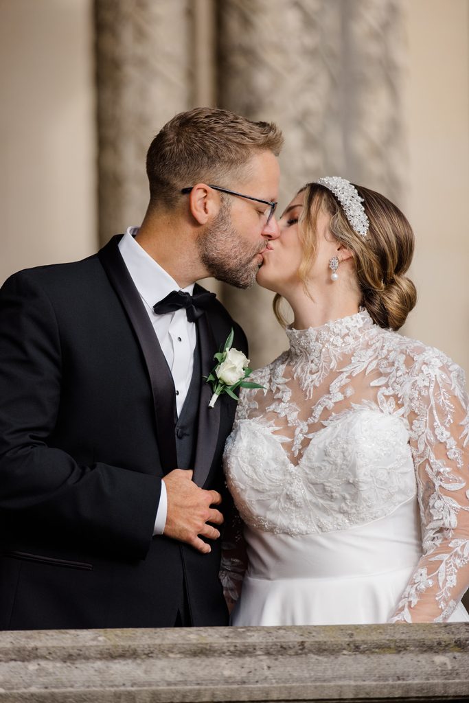 bride and groom kissing, bride has a beauitful lace gown and white beaded headband