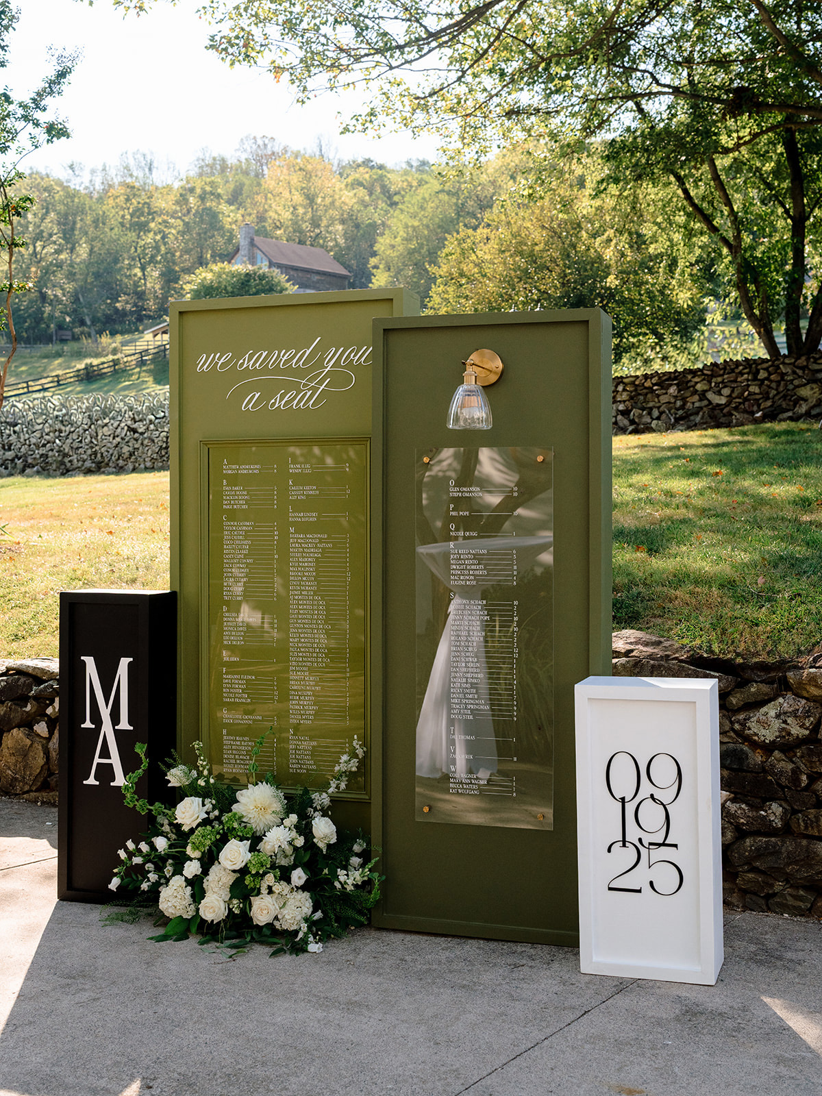 Large green installation of wedding seating chart with details like sconces and plexiglass