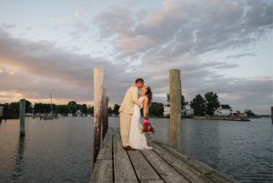 Bride and groom kissing on a wooden dock at sunset on the Eastern Shore, with waterfront views and soft evening light