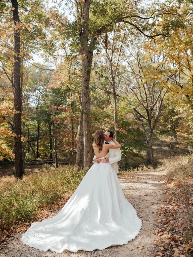 A bride in a Mia Grace Bridal gown embraces her groom outside in the natural landscape at Silver Oaks Chateau.