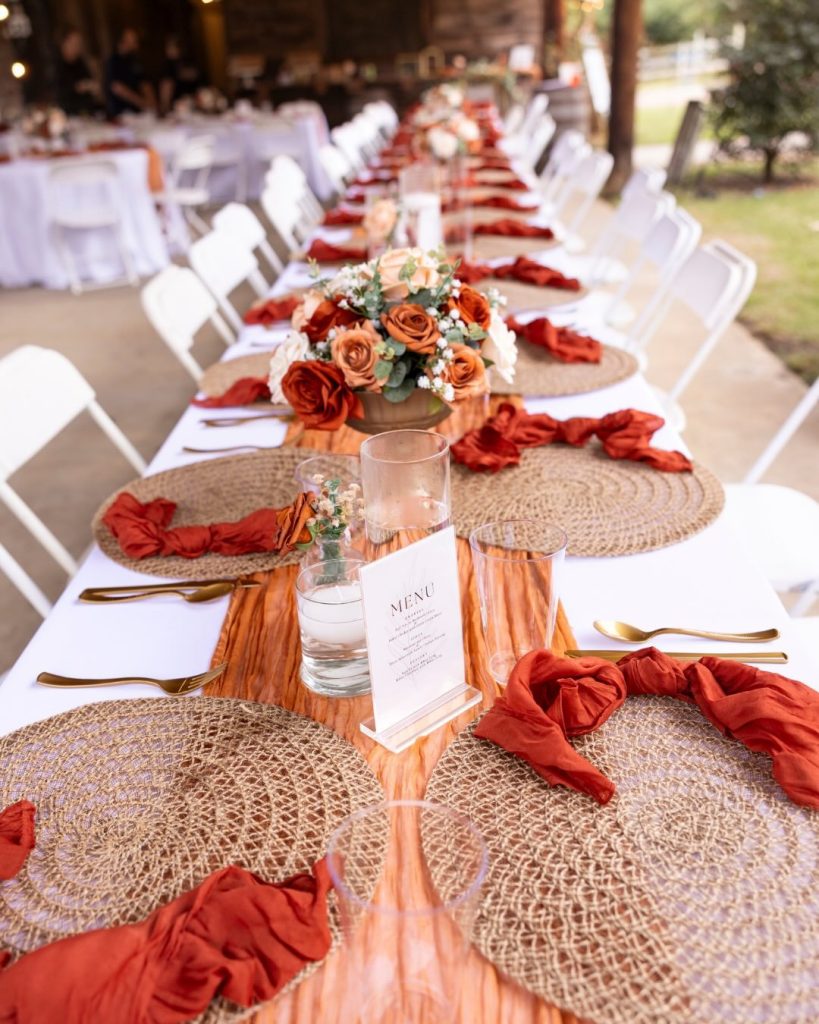 reception table with orange napkins and boho chargers