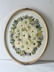Florals pressed in a gold oval frame for flower preservation