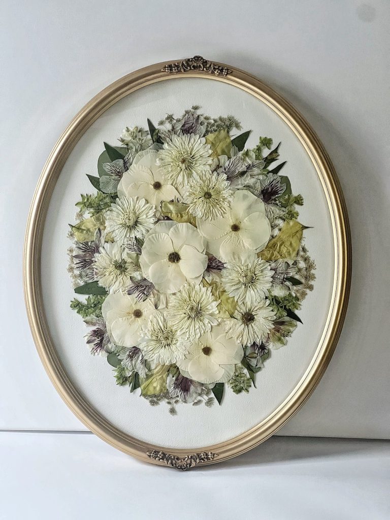 Florals pressed in a gold oval frame for flower preservation