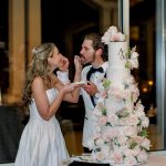 husband and wife eating multi-tiered wedding cake