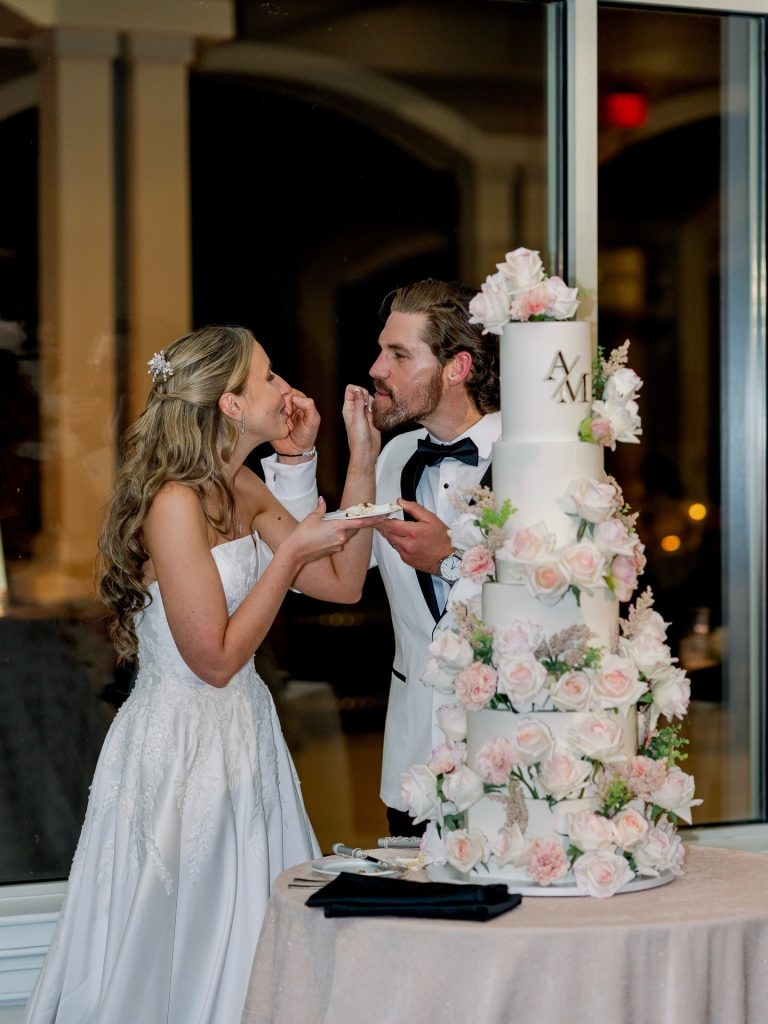 husband and wife eating multi-tiered wedding cake