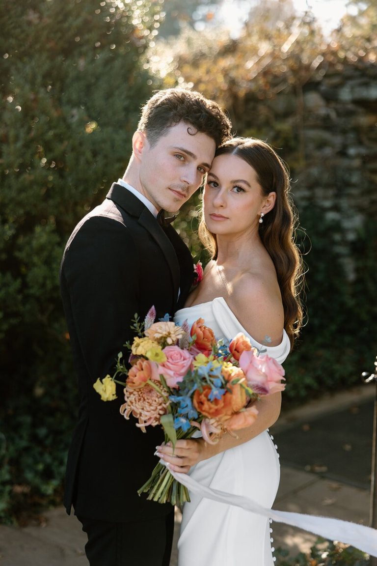 bride and groom taking outdoor wedding portraits after ceremony with color floral bouquet