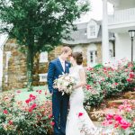 Bride and Groom taking photos on outdoor steps with flowers all around