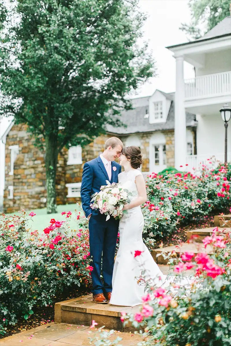 Bride and Groom taking photos on outdoor steps with flowers all around