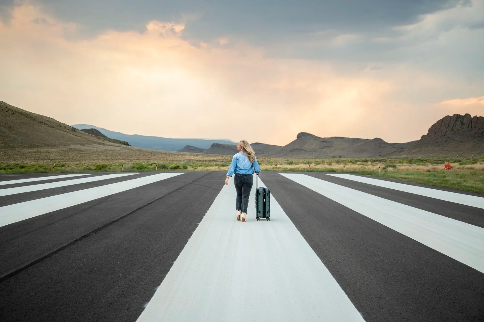 Woman traveling with suitcase walking on airplane runway