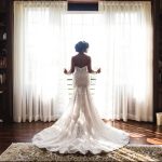 Bride looking out window showing back of wedding dress with train