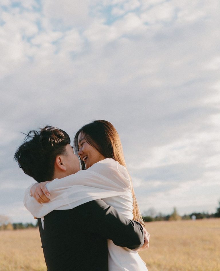 Couple holding each other in a field for engagement photo session