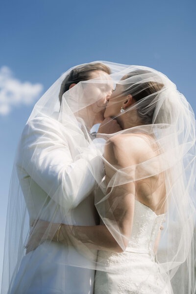 bride kissing groom under wedding veil