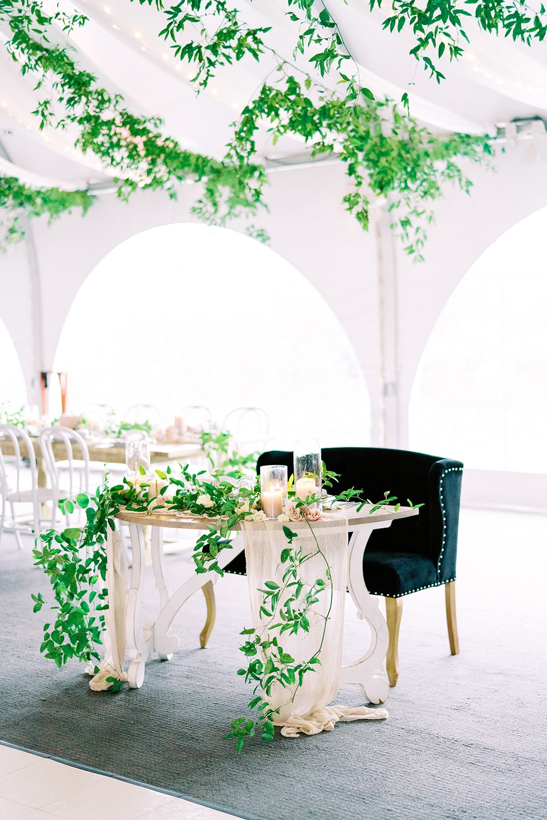 Outdoor Tented Wedding reception with greenery and couples couch at sweetheart table