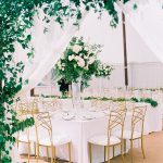 Tented outdoor reception with white tablecloths and gold chairs