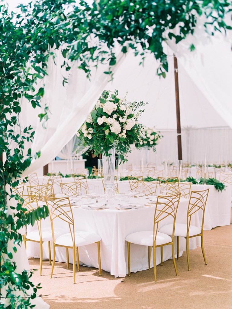 Tented outdoor reception with white tablecloths and gold chairs