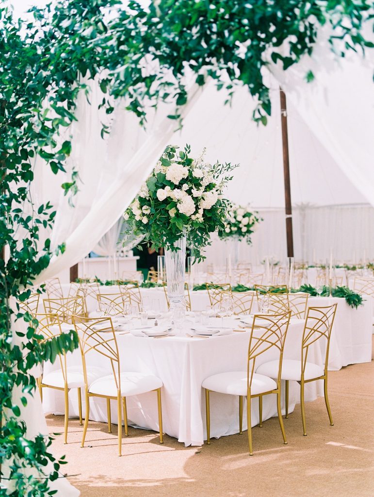 Tented outdoor reception with white tablecloths and gold chairs