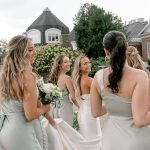 Bride and bridemaids walking to ceremony while holding wedding dress train