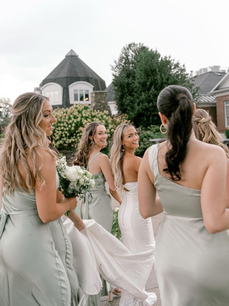Bride and bridemaids walking to ceremony while holding wedding dress train