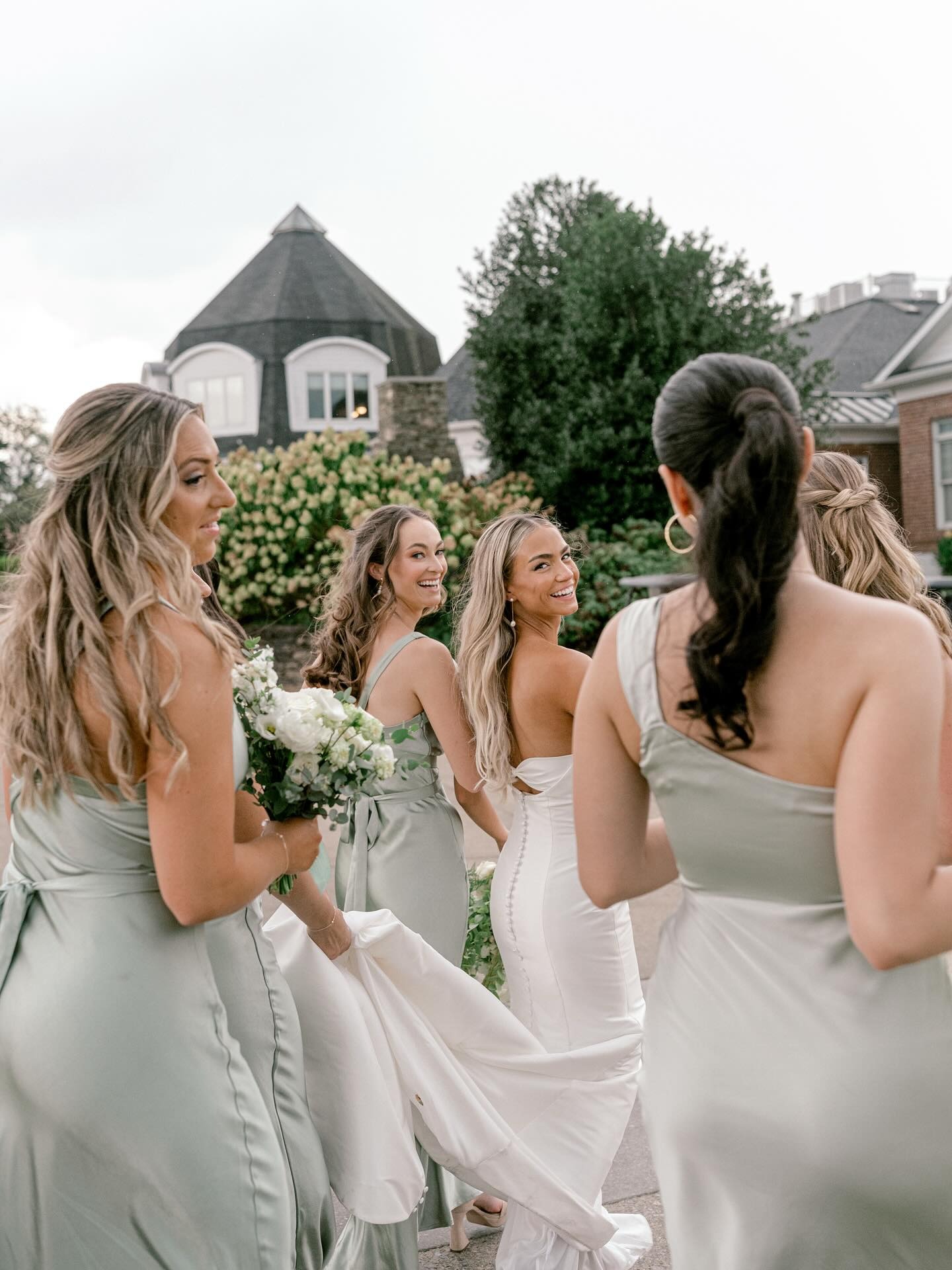 Bride and bridemaids walking to ceremony while holding wedding dress train