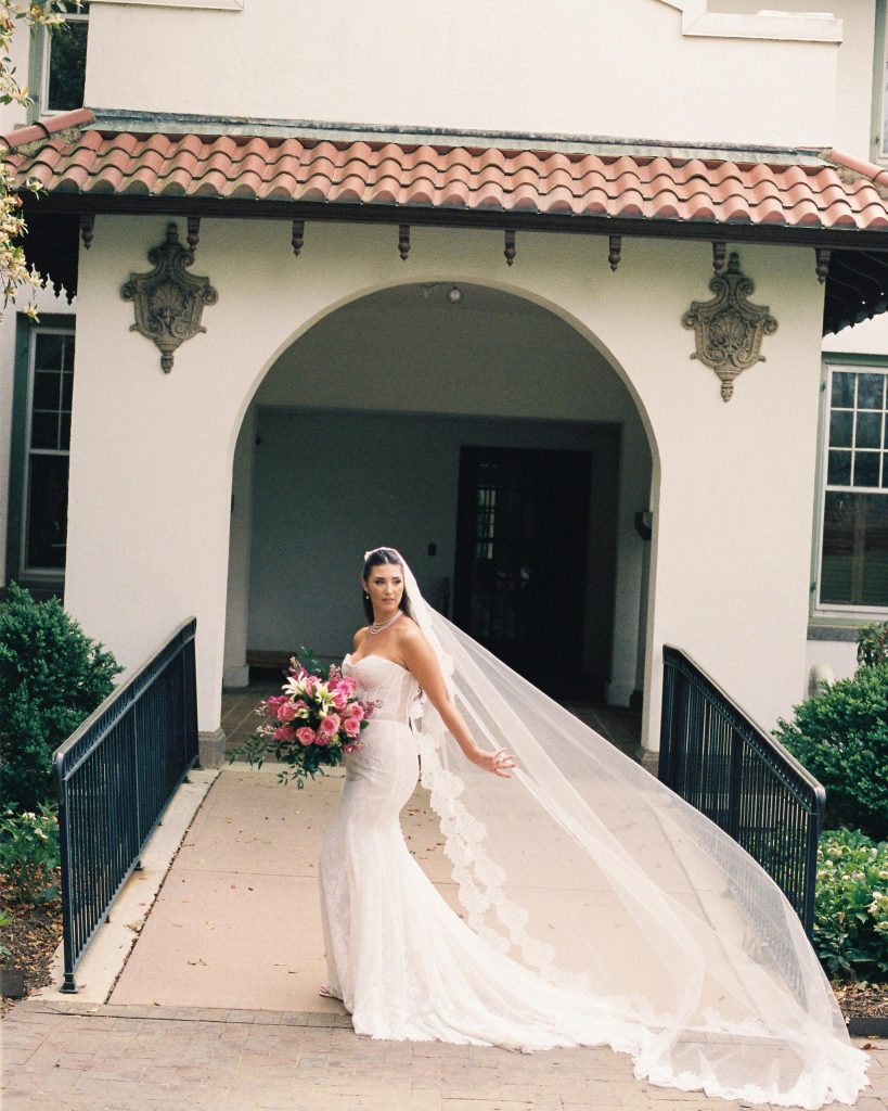 bride with a long flowing veil in front of a spanish inspired venue