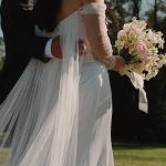groom holding bride lower back focusing on dress flowing details