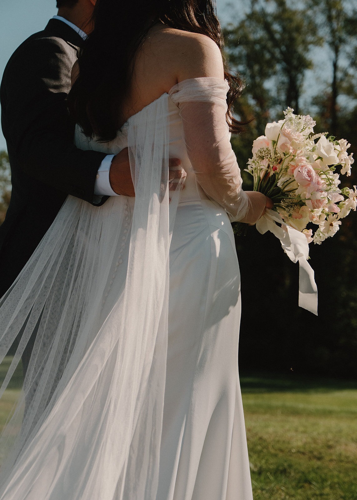 groom holding bride lower back focusing on dress flowing details