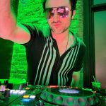 dj with dj spin board with sunglasses and green lighting
