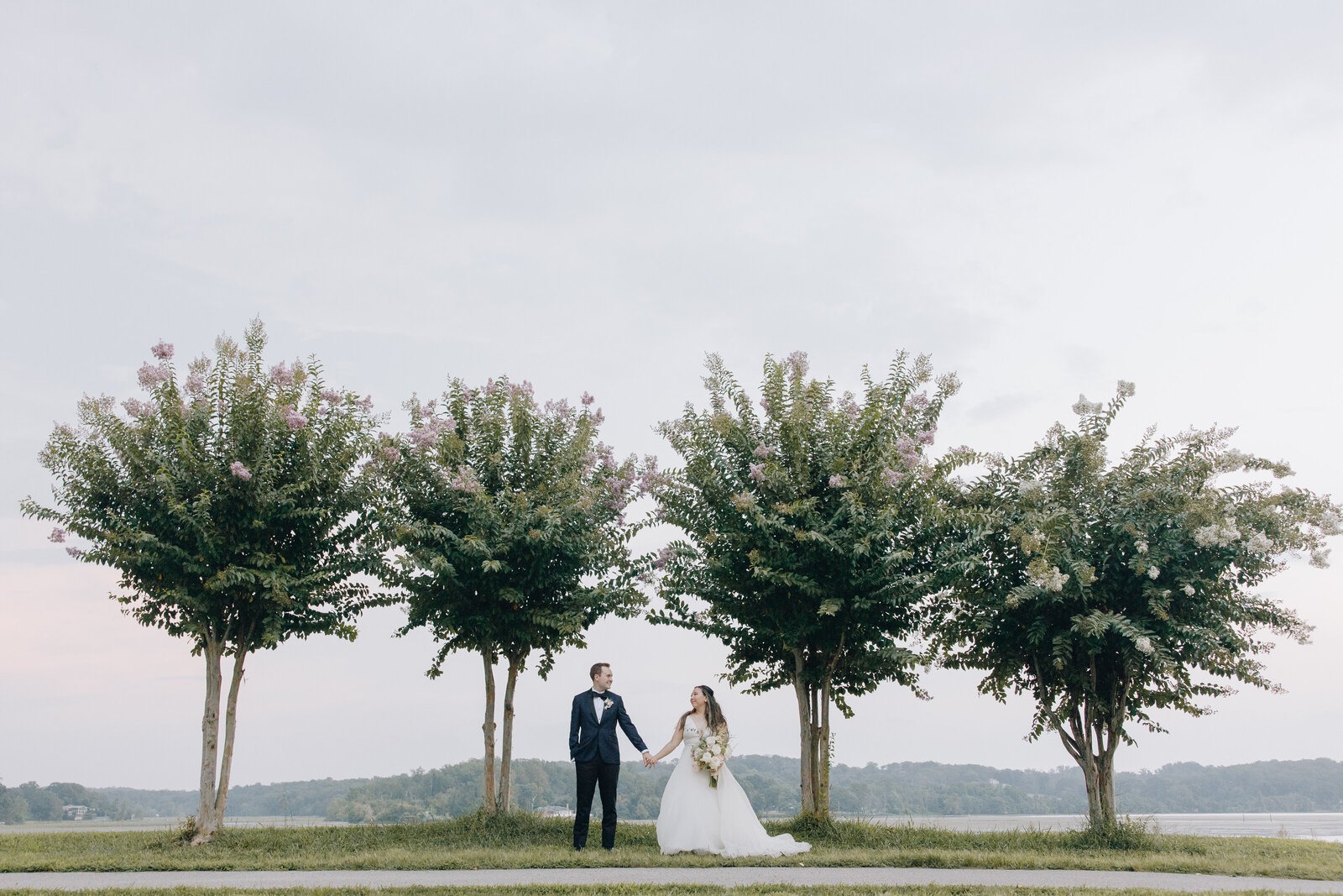 bride and groom taking outdoor wedding portraits near trees at golf course in northern virginia