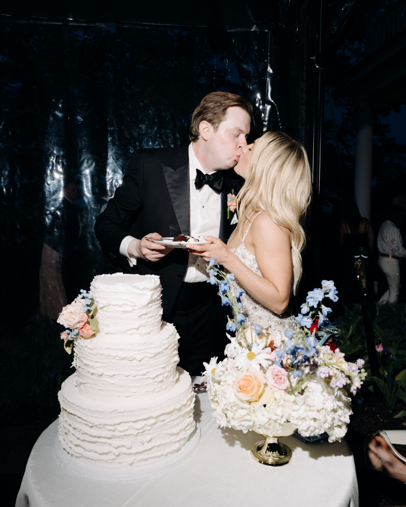 Bride and Groom sharing kiss while cutting their three tier wedding cake