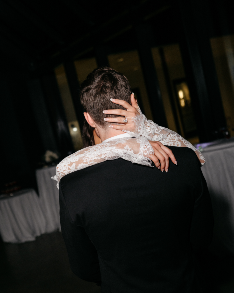 Romantic wedding moment with bride embracing groom in black tie attire