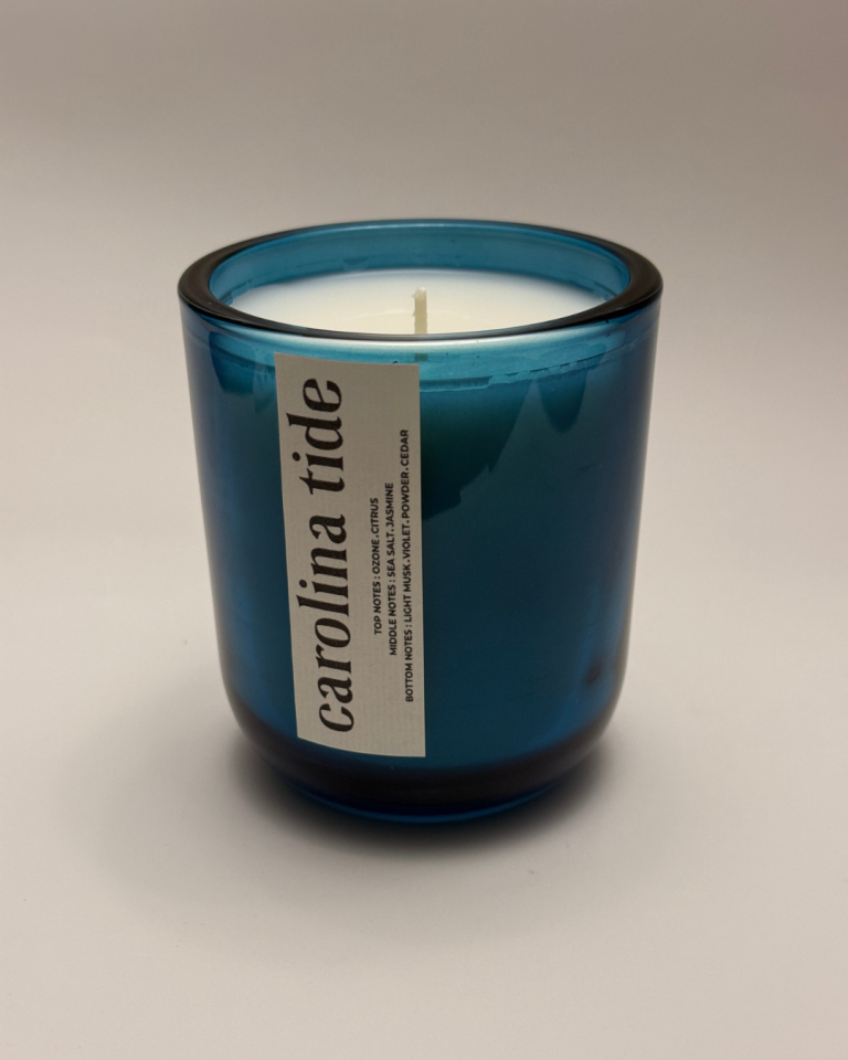 "Carolina Tide" candle in a deep cerulean blue glass jar with a white vertical label and scent profile.