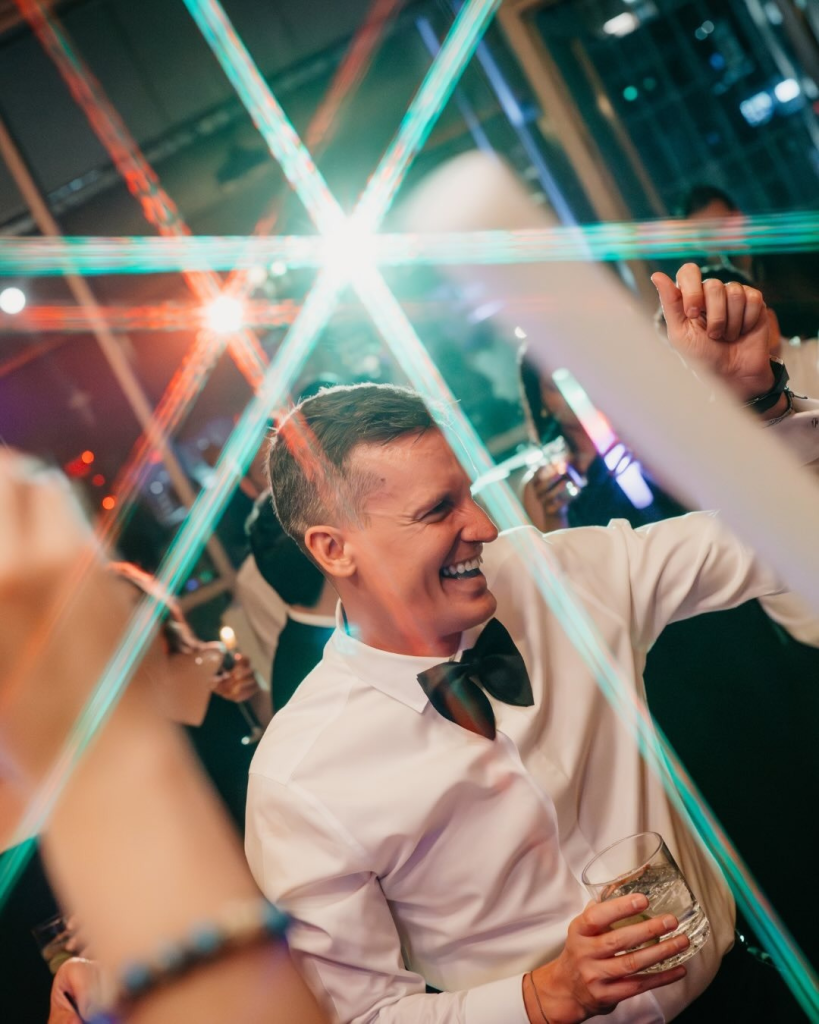 Reception dance floor portrait with colorful lighting and joyful celebration during Eric and Kyle's Charlotte wedding reception.