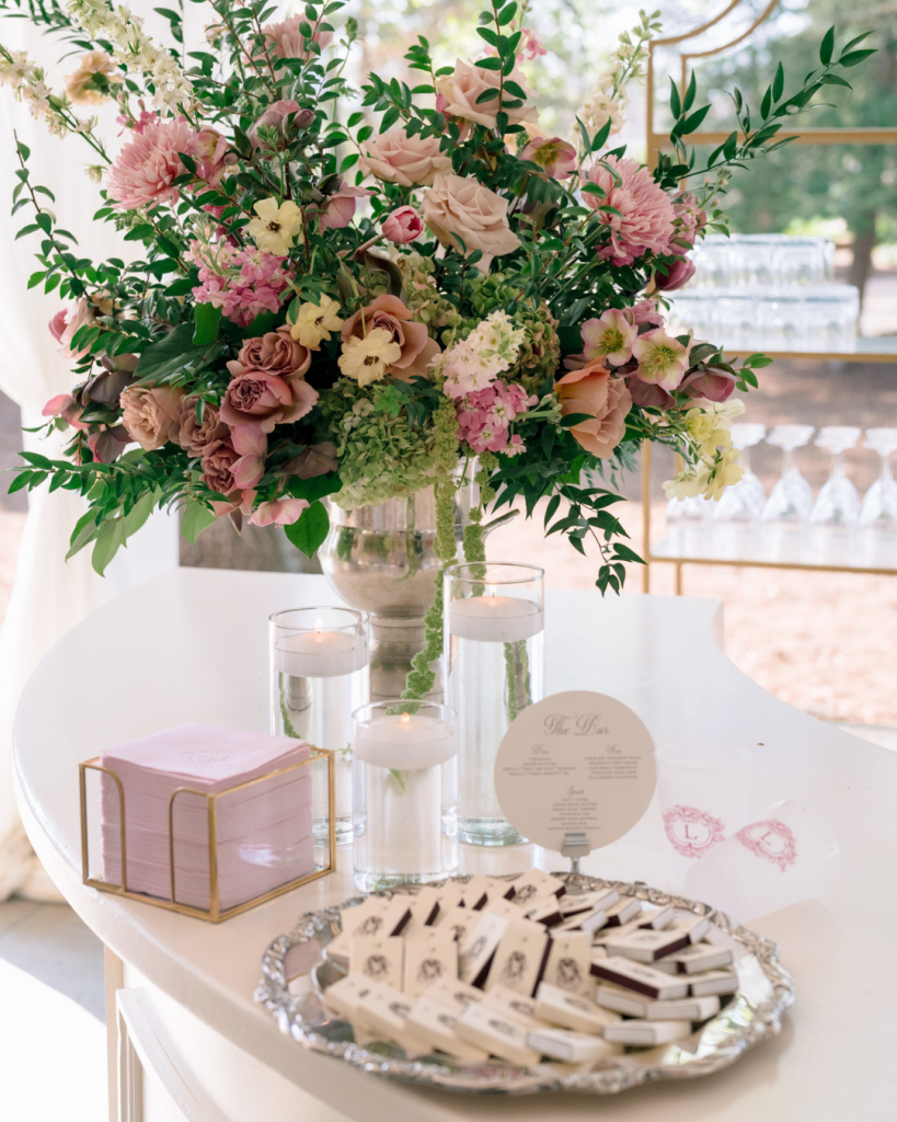 Colorful spring floral arrangement displayed on the wedding bar with candles and personalized cocktail napkins.