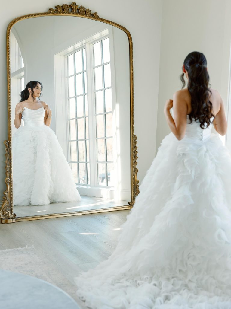 Bride in full ballgown looking at herself in the mirror.
