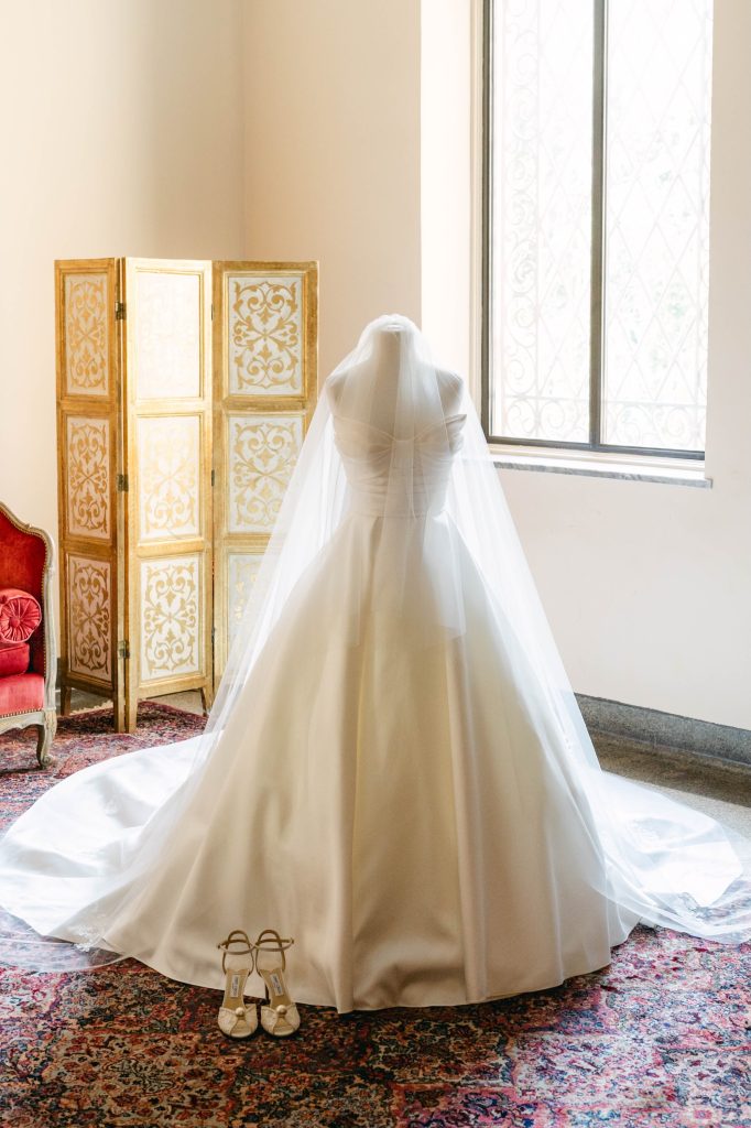 Wedding gown displayed on a mannequin with a cathedral-length veil in a bright bridal suite featuring vintage décor and natural light.