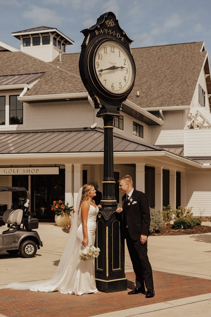 Bride and groom posing beneath Bayside Resort Golf Club clock in Selbyville Delaware