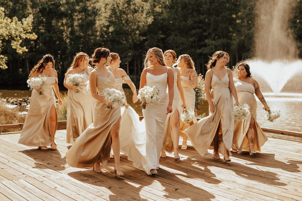 Bridesmaids walking beside bride in satin dresses during golden hour portraits at Bayside Resort Golf Club