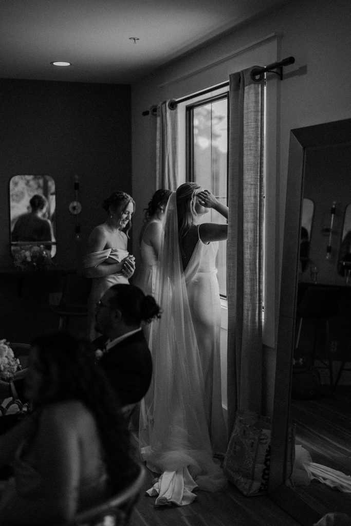 Black and white bridal suite moment with bride and bridesmaids gathered by window before ceremony