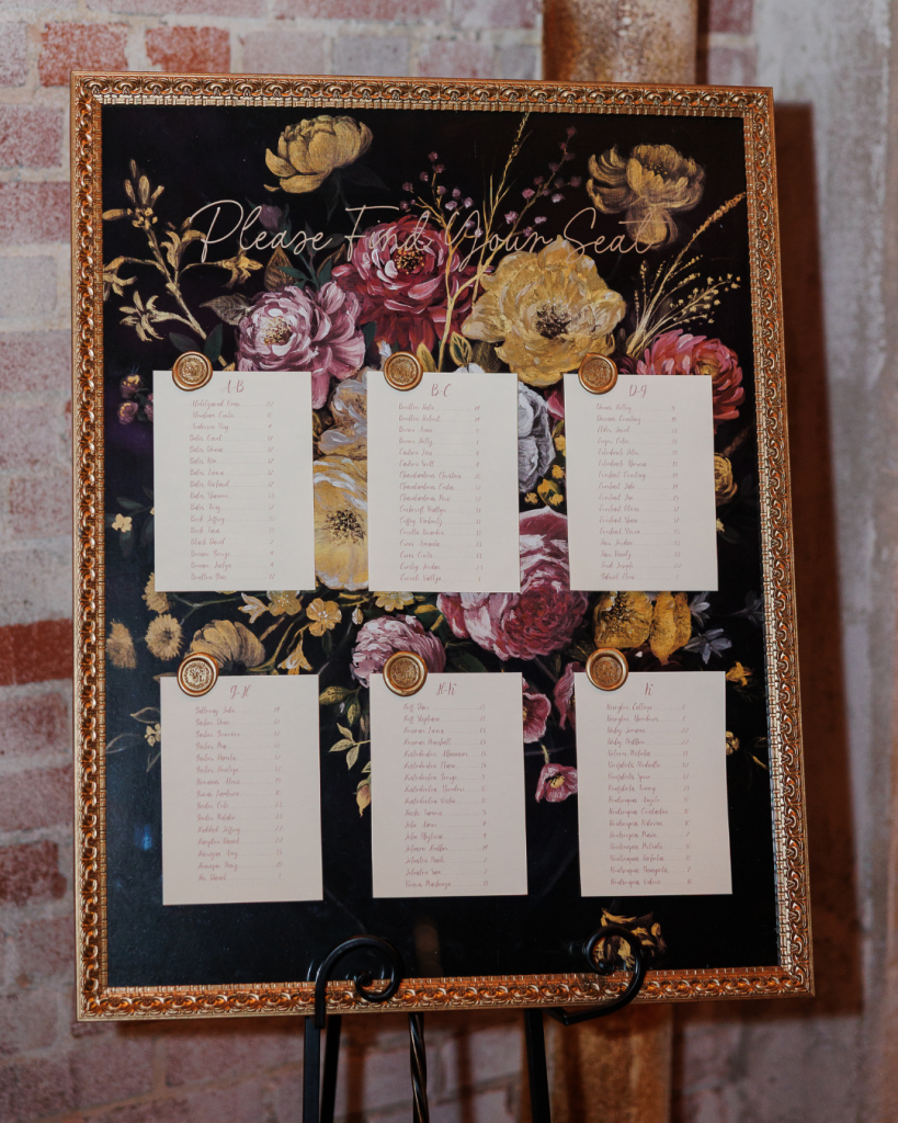 Floral inspired wedding seating chart with gold frame and romantic artwork displayed at The Revelry wedding reception in Charlotte.