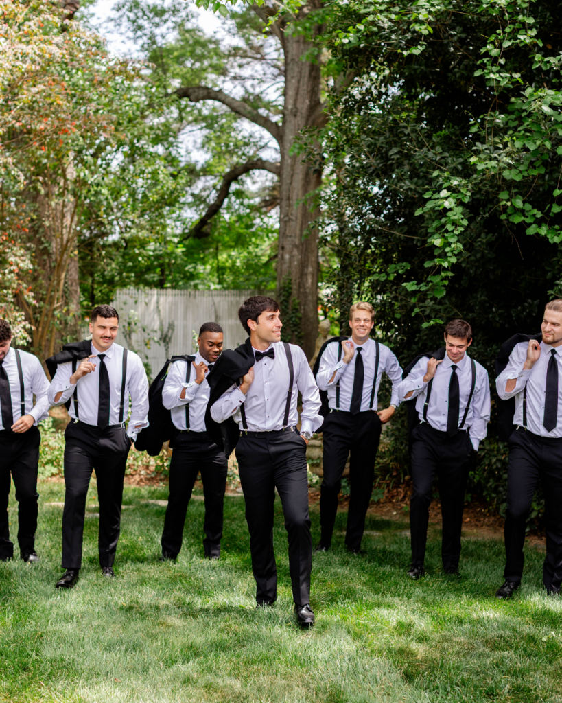 Groom walking with groomsmen outdoors before the ceremony at The Grande Victorian wedding venue.
