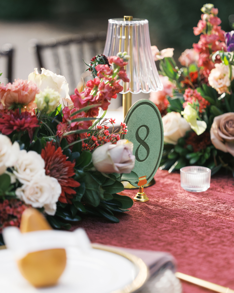 Elegant wedding reception centerpiece with colorful florals, gold accents, table lamp decor, and velvet inspired linens at a Charlotte wedding.