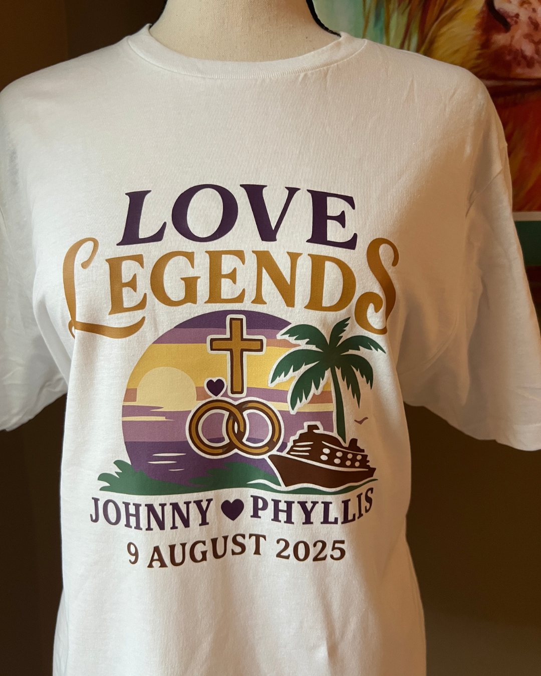 White tee with "Love Legends" graphic, wedding rings, a cross, and a cruise ship at sunset for Johnny and Phyllis.