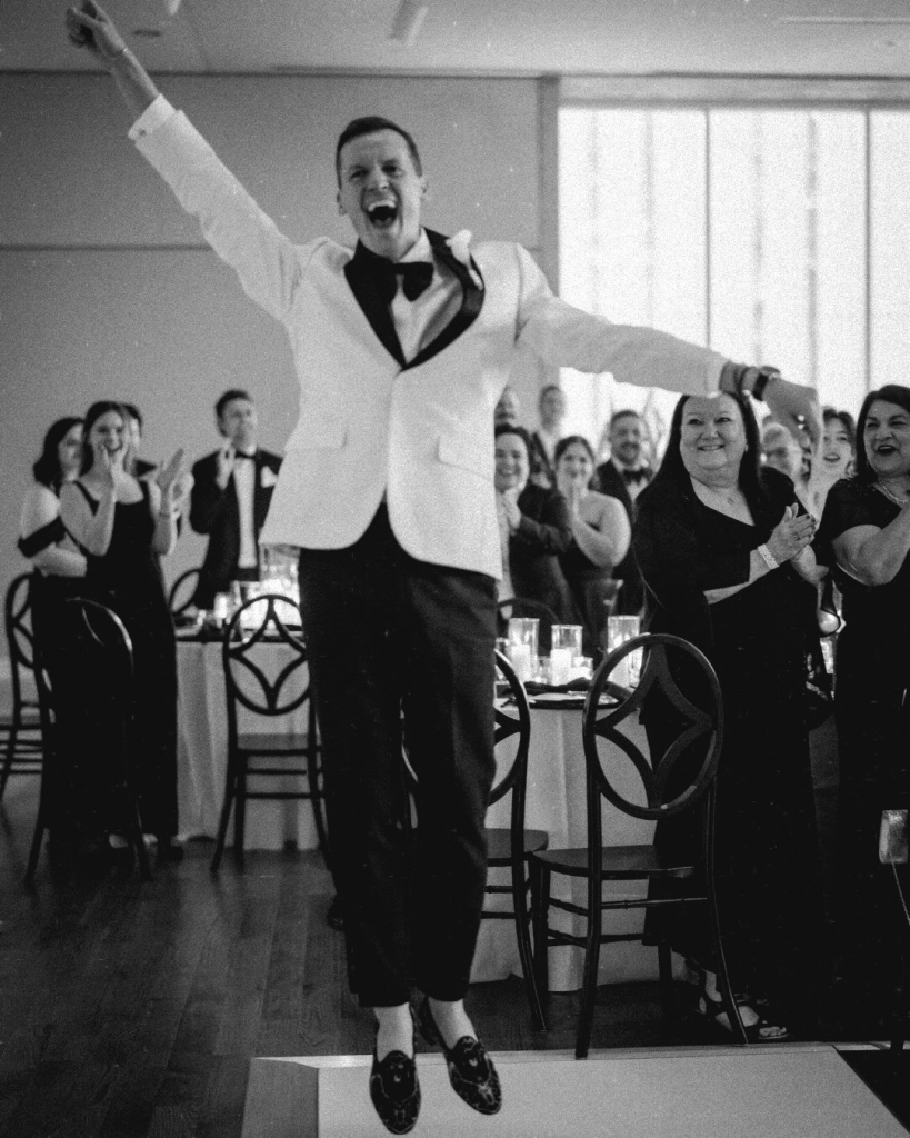 Reception moment showing a groom celebrating on the dance floor during a modern black tie wedding reception in Charlotte.