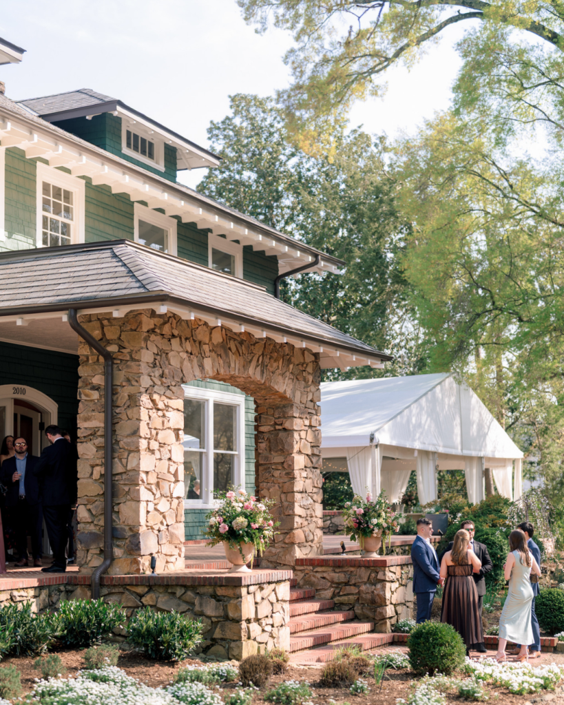 Guests gather outside Van Landingham Estate during cocktail hour with spring florals decorating the historic home.