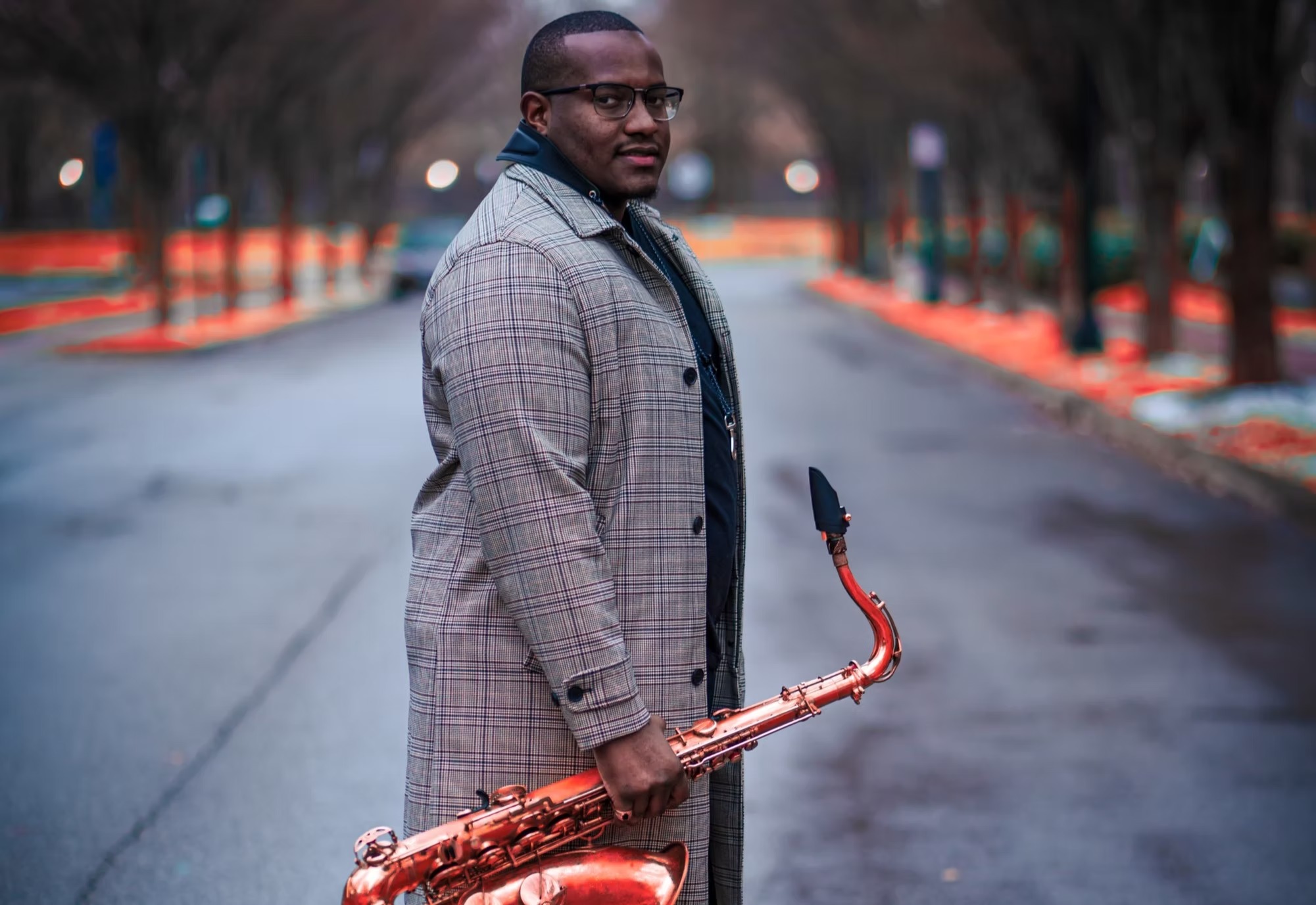 Anthony Saxson holding a saxophone on a city street.