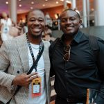 Anthony Saxson posing with a fellow attendee at a music industry event.