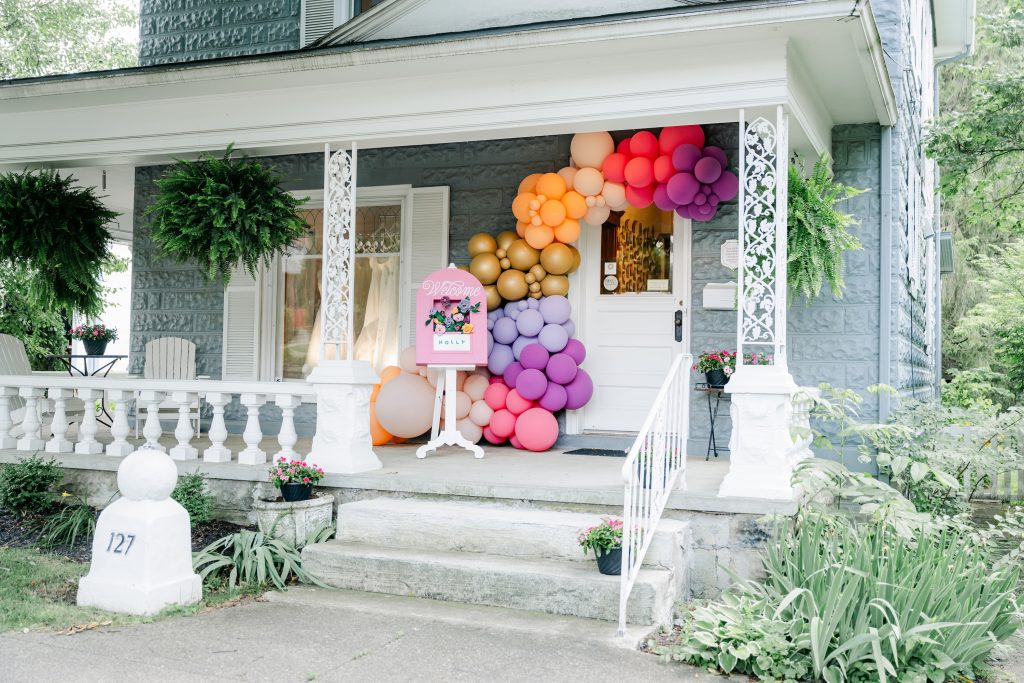 Exterior of Gilded Social bridal boutique decorated with colorful balloon installations and a welcome sign for a bridal event in Granville, Ohio.