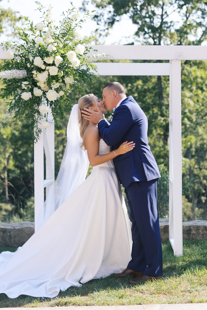 Bride and groom first kiss at an outdoor ceremony at Silver Oaks Chateau. Captured by Emily Blackford Photography.